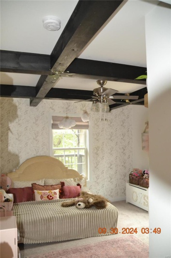 Bedroom with carpet, ceiling fan, and beamed ceiling