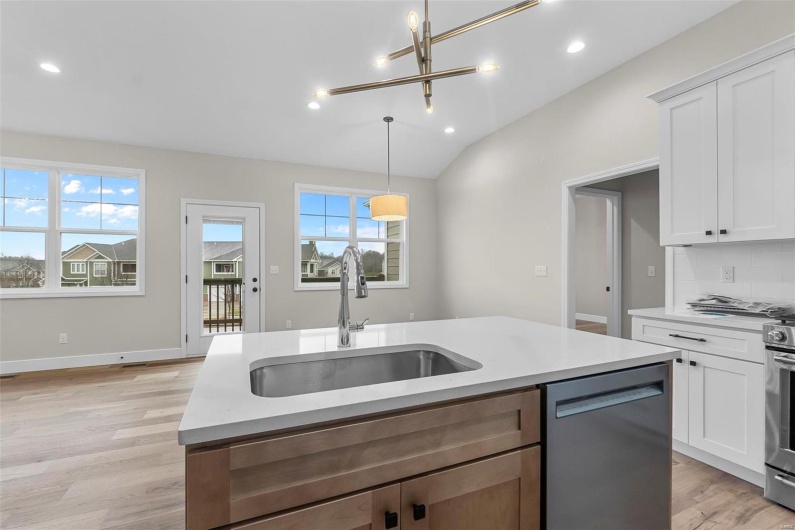Kitchen with white cabinetry, sink, stainless steel appliances, and decorative light fixtures