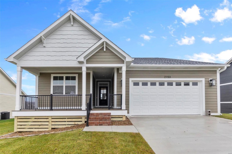 View of front facade featuring a garage, covered porch, central air condition unit, and a front yard