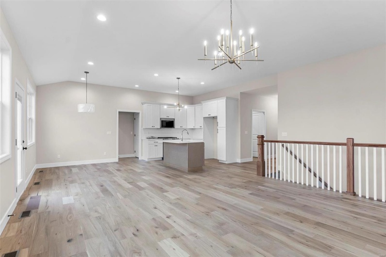 Kitchen with white cabinetry, a kitchen island with sink, decorative light fixtures, and light wood-type flooring