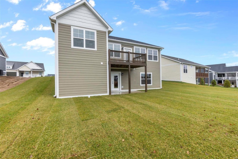 Back of property featuring a balcony and a yard