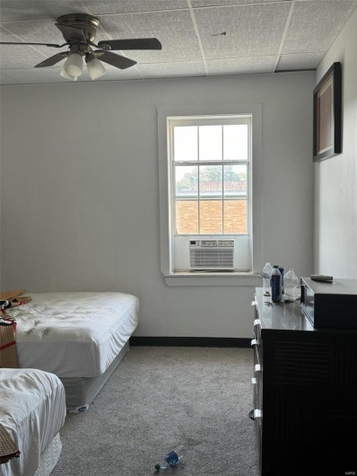 Bedroom featuring a paneled ceiling, light carpet, cooling unit, and ceiling fan