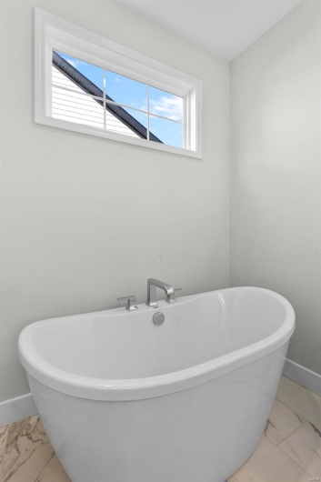 Full bathroom featuring baseboards, marble finish floor, a freestanding bath, and a healthy amount of sunlight