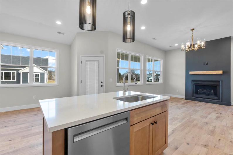 Kitchen with a fireplace, light wood-style flooring, open floor plan, a sink, and dishwasher