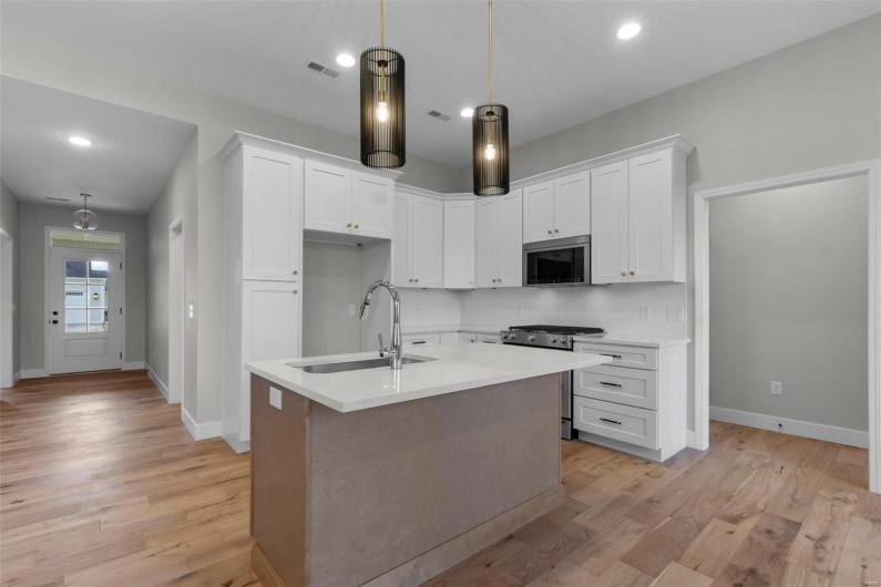 Kitchen featuring visible vents, white cabinets, light wood-style flooring, appliances with stainless steel finishes, and a sink