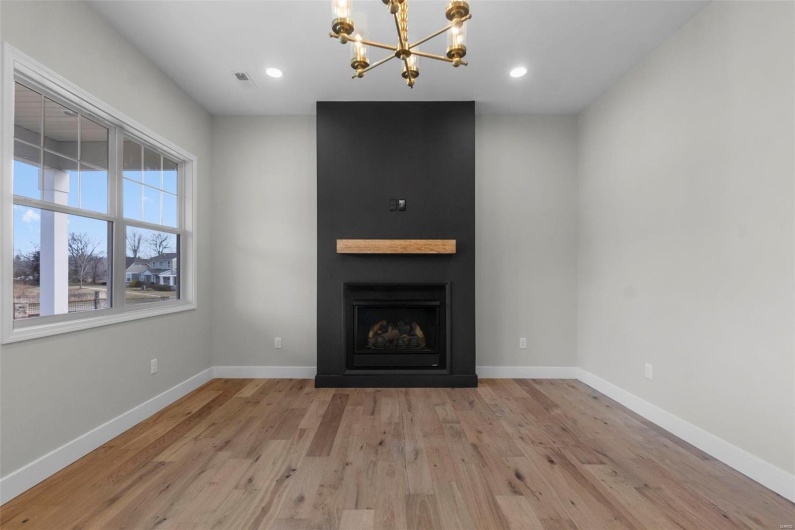 Unfurnished living room with a large fireplace, light wood-style flooring, and baseboards
