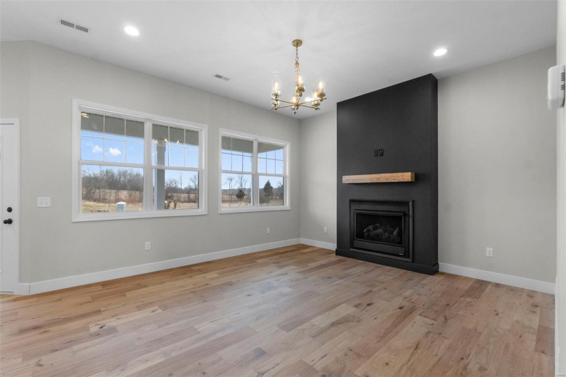 Unfurnished living room with light wood-style flooring, a fireplace, baseboards, and a wealth of natural light