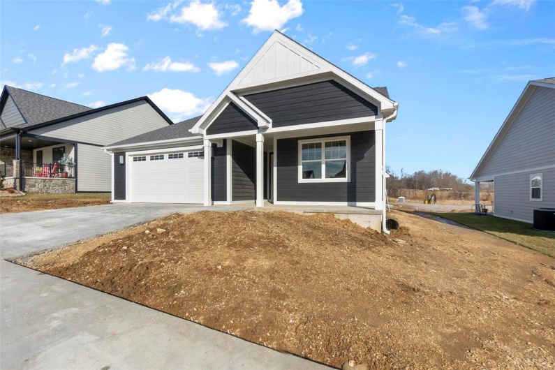 View of front facade featuring driveway, a garage, a porch, and board and batten siding