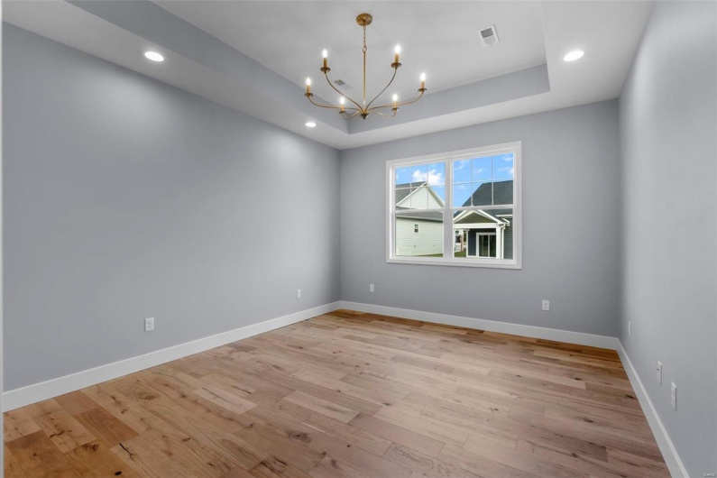 Unfurnished room featuring a tray ceiling, recessed lighting, light wood-style flooring, and baseboards
