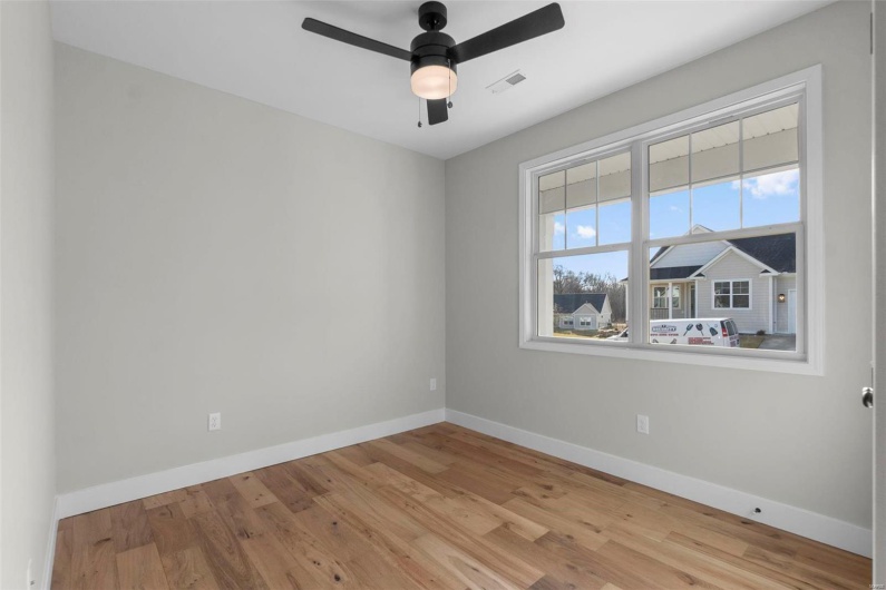 Empty room featuring a ceiling fan, wood finished floors, visible vents, and baseboards