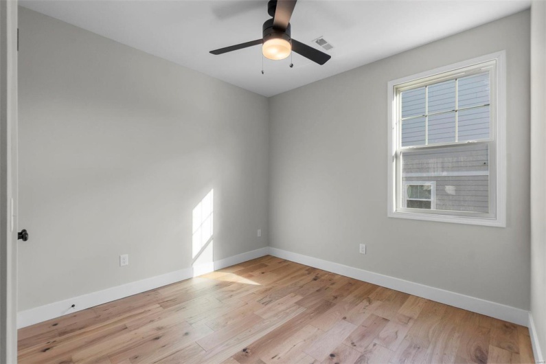 Empty room with light wood finished floors, baseboards, visible vents, and ceiling fan