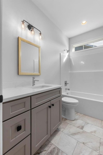 Bathroom featuring marble finish floor, vanity, bathtub / shower combination, and toilet