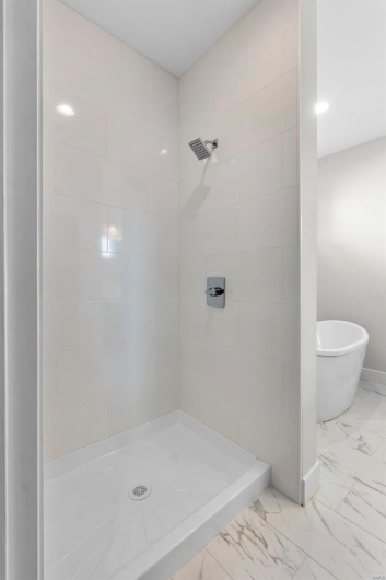 Bathroom with a stall shower, marble finish floor, a freestanding tub, and baseboards