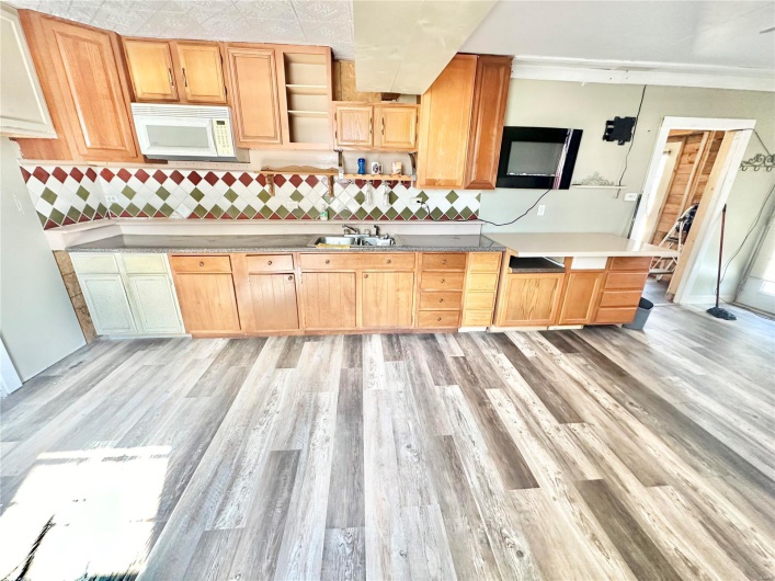 Kitchen featuring light brown cabinets, ornamental molding, sink, backsplash, and light wood-type flooring