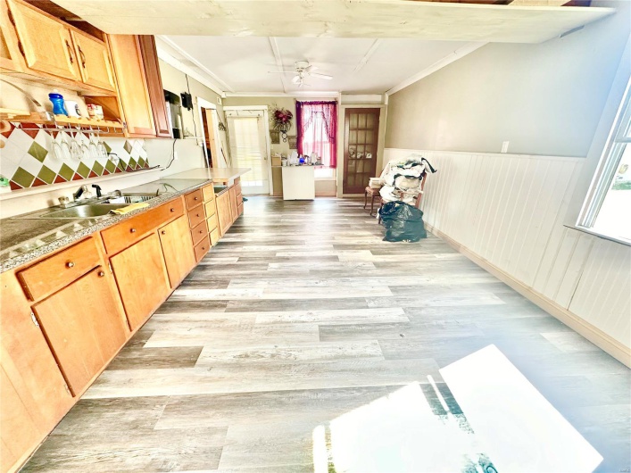 Kitchen featuring ceiling fan, ornamental molding, sink, and light hardwood / wood-style floors