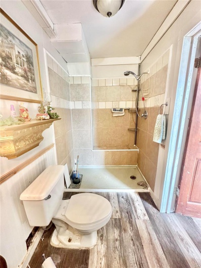Bathroom with wood-type flooring, toilet, and a tile shower