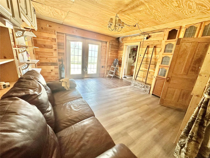 Living room featuring wood ceiling, a notable chandelier, wooden walls, french doors, and hardwood / wood-style flooring
