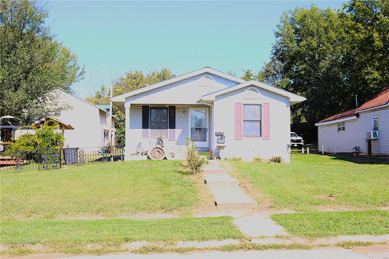 View of front facade featuring cooling unit and a front yard