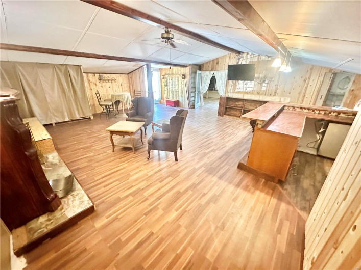 Dining space with lofted ceiling with beams, ceiling fan, wood walls, and wood-type flooring