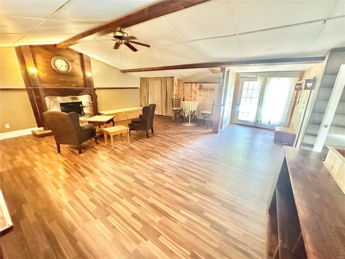 Living area with lofted ceiling with beams, hardwood / wood-style flooring, and ceiling fan