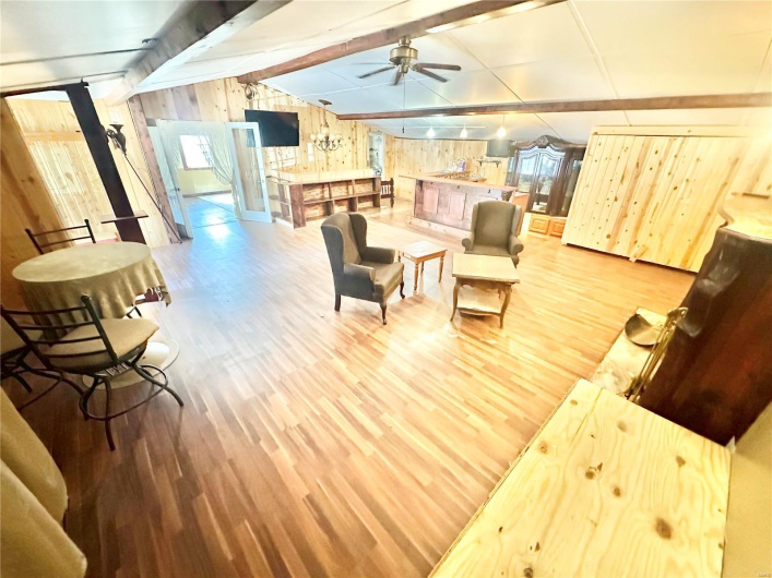 Living room featuring wood walls, lofted ceiling with beams, and light hardwood / wood-style flooring