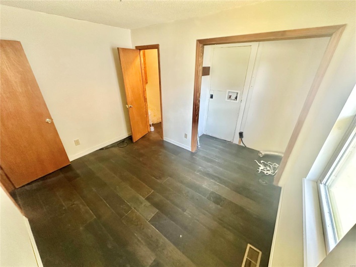 Spare room featuring a textured ceiling and dark hardwood / wood-style floors