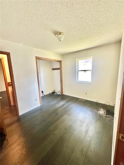 Unfurnished bedroom featuring dark wood-type flooring, a closet, and a textured ceiling