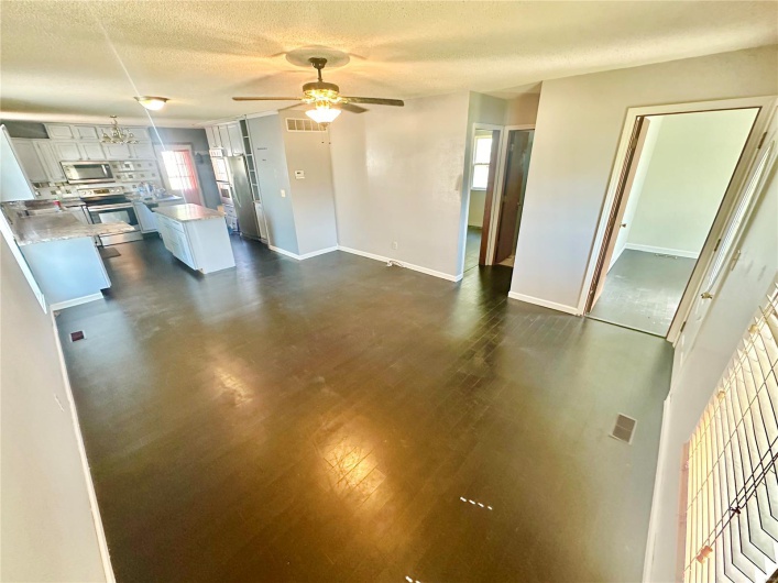 Unfurnished living room featuring ceiling fan, dark hardwood / wood-style floors, and a textured ceiling