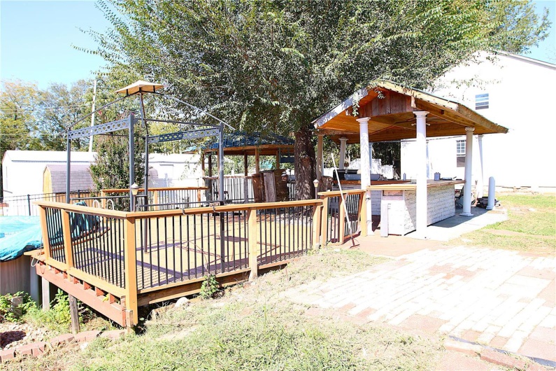 Wooden terrace with a gazebo, a shed, and a patio area