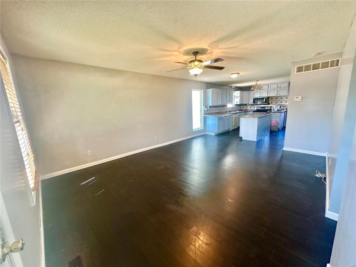 Kitchen with ceiling fan, a center island, dark hardwood / wood-style floors, and a textured ceiling