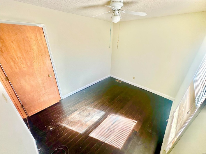 Empty room featuring a textured ceiling, ceiling fan, and dark hardwood / wood-style flooring