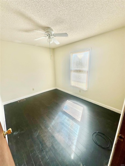 Empty room featuring ceiling fan, hardwood / wood-style floors, and a textured ceiling
