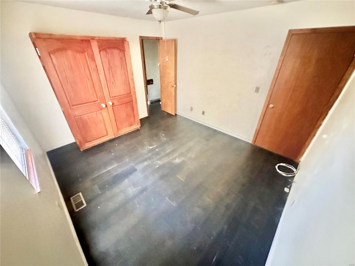 Unfurnished bedroom featuring ceiling fan and dark wood-type flooring