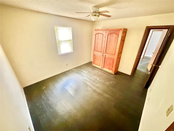 Unfurnished bedroom featuring ceiling fan, a textured ceiling, and dark hardwood / wood-style floors