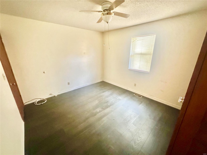 Unfurnished room featuring dark wood-type flooring, a textured ceiling, and ceiling fan