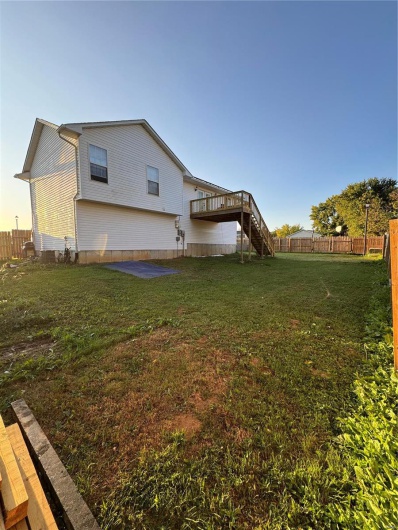 View of side of property with a yard and a wooden deck