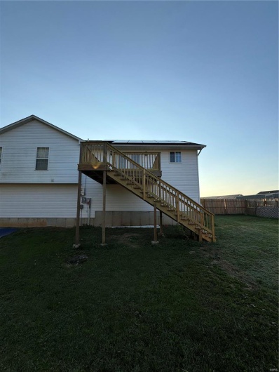 Back house featuring a wooden deck and a lawn
