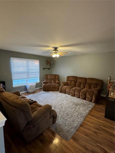 Living room with ceiling fan and dark wood-type flooring