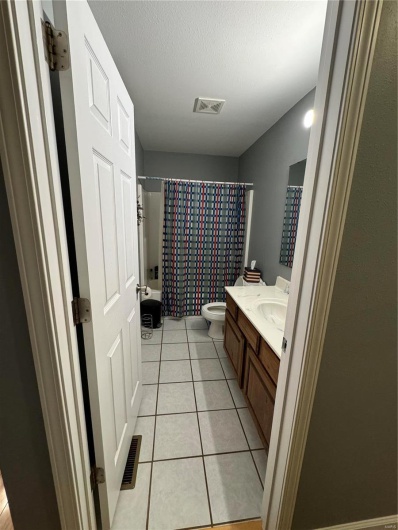 Full bathroom featuring tile patterned flooring, a textured ceiling, shower / tub combo, vanity, and toilet