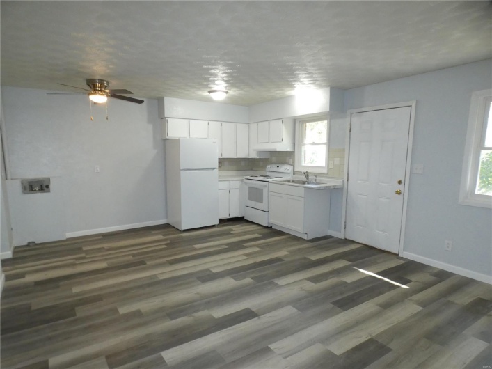 Kitchen featuring dark hardwood / wood-style flooring, white appliances, sink, and white cabinets