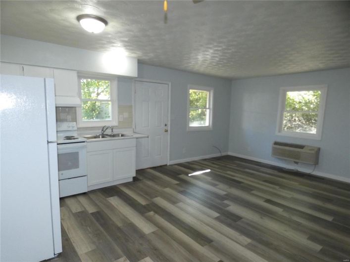 Kitchen featuring white appliances, a healthy amount of sunlight, dark hardwood / wood-style flooring, and white cabinetry