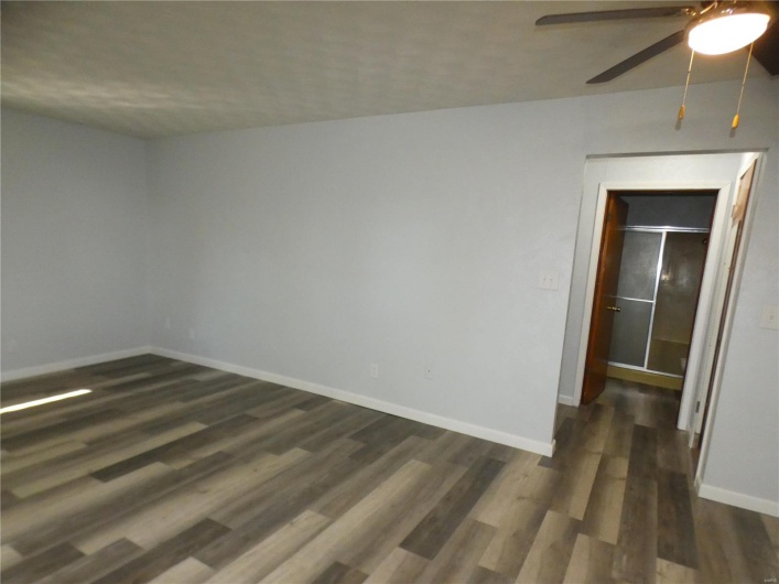 Empty room with ceiling fan and dark wood-type flooring