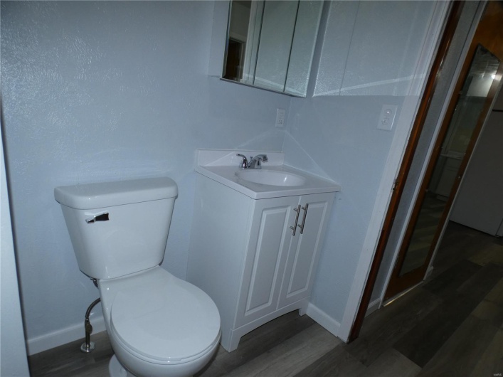 Bathroom with hardwood / wood-style floors, vanity, and toilet
