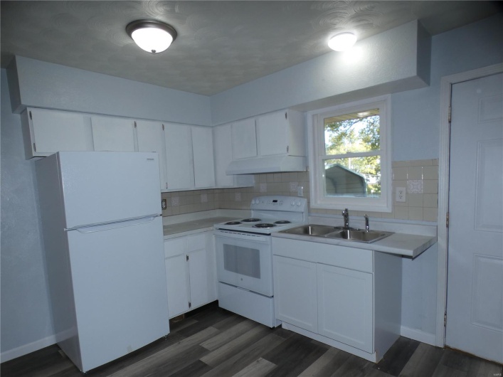 Kitchen featuring decorative backsplash, white appliances, sink, and white cabinetry