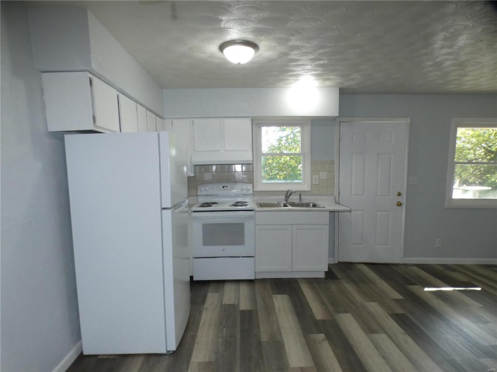Kitchen featuring sink, white appliances, white cabinetry, and tasteful backsplash