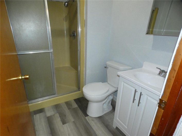 Bathroom with hardwood / wood-style flooring, toilet, walk in shower, and vanity