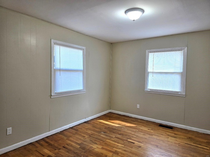 Unfurnished room with hardwood / wood-style flooring, a wealth of natural light, and wooden walls