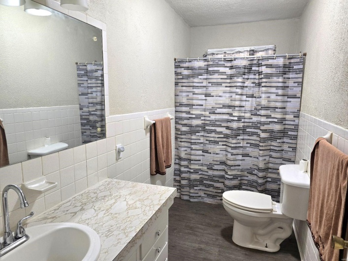 Bathroom featuring wood-type flooring, a textured ceiling, toilet, tile walls, and vanity