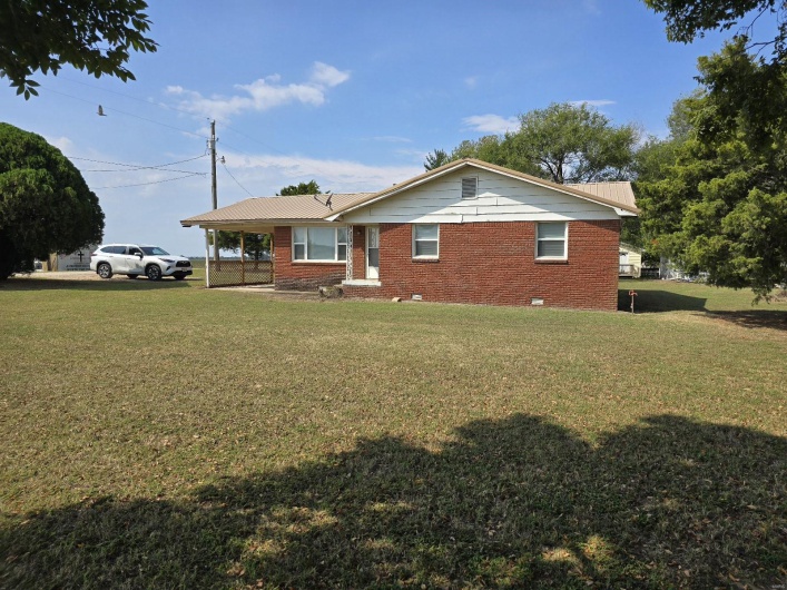 View of front of house with a front yard and a carport