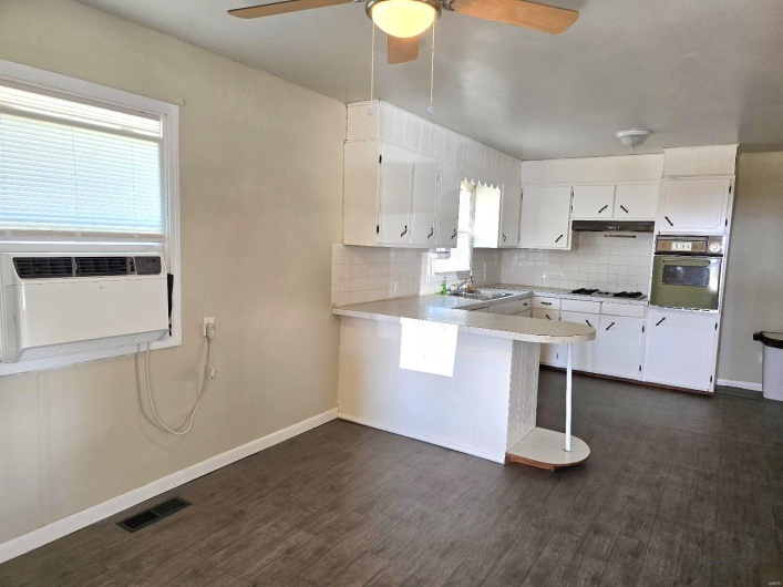 Kitchen featuring kitchen peninsula, white cabinetry, wall oven, and a breakfast bar